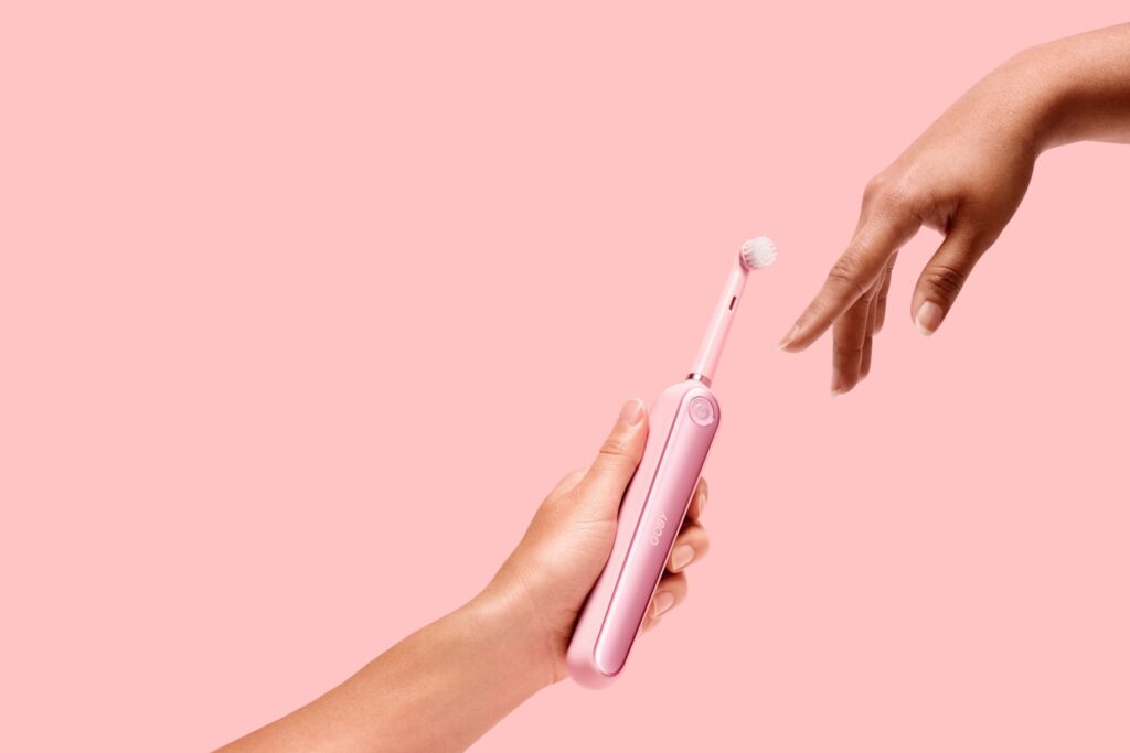 person holding pink electric toothbrush